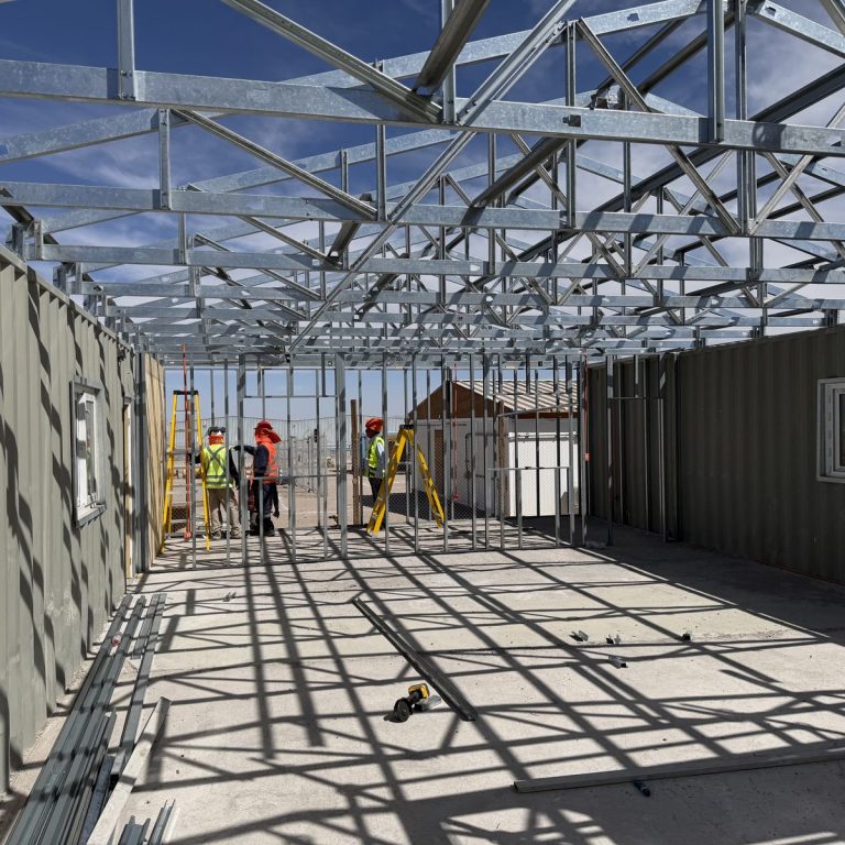 Personal con equipo de protección en montaje de techumbre metálica de faena